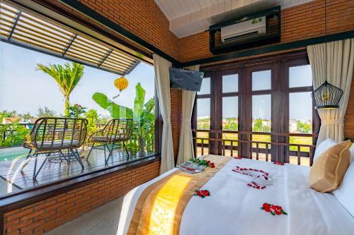 a bedroom with a bed and a large window at Angel Garden Villa in Hoi An