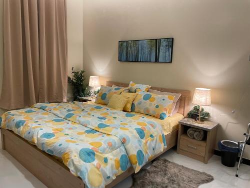 1 dormitorio con 1 cama con edredón y 2 lámparas en تل النسيم Hill Breeze, en Abha