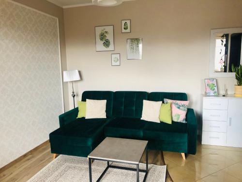a green couch in a living room with a table at Apartament słoneczny in Olsztyn
