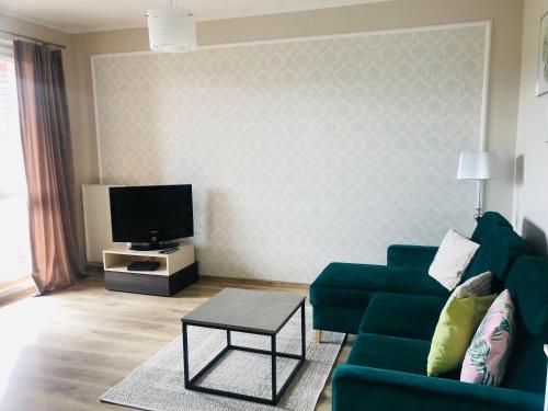 a living room with a green couch and a tv at Apartament słoneczny in Olsztyn