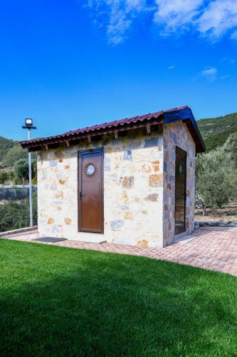a small stone building with a door and grass at Pinelia Home in Mirtófiton
