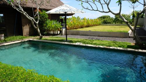einen Pool im Garten mit Sonnenschirm in der Unterkunft Kultur Pecatu Micro Villa in Uluwatu