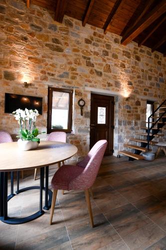 a room with a table and chairs and a stone wall at Pinelia Home in Mirtófiton
