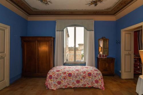 a blue bedroom with a bed and a window at Palazzo Romani Adami in Fermo