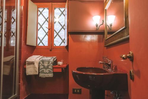 a red bathroom with a sink and a mirror at Palazzo Romani Adami in Fermo
