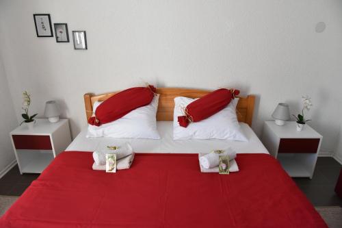 a bedroom with a red and white bed with red pillows at Apartment Bobic in Ličko Petrovo Selo