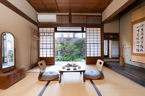 a living room with a table and chairs and windows at Higurashi-sou in Kyoto
