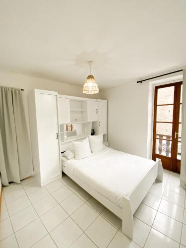 une chambre blanche avec un lit blanc et une fenêtre dans l'établissement La casa de León, à Sarlat-la-Canéda