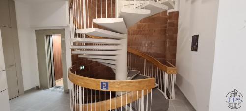 a spiral staircase in a building with a wooden railing at Le Phare Dieppois by JPS Holiday - Chaleureux appartement au cœur de Dieppe in Dieppe