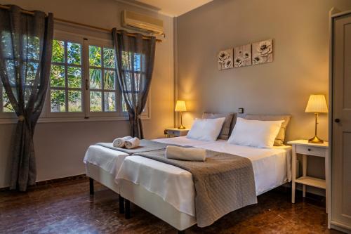 a bedroom with a large white bed with two windows at Blue Sky in Sidari