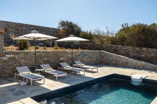 a patio with chairs and umbrellas next to a pool at Nevermind Vacations villa A in Kastrianí
