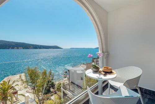 a table and chairs on a balcony with a view of the water at Hotel Perla in Herceg-Novi