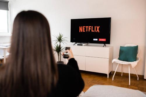 a woman taking a picture of a television with her cell phone at - NEU - Sweet Home, Parkplatz, Netflix in Bad Salzuflen