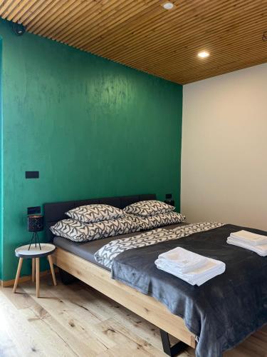 a bedroom with a large bed with a green wall at Downhills Residence in Zázrivá