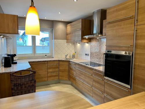 a kitchen with wooden cabinets and a black appliance at JUNIPRO Apartments Haustadt in Beckingen