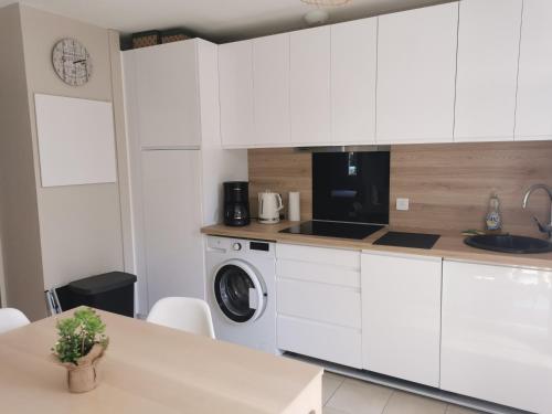 une cuisine avec des armoires blanches et une machine à laver dans l'établissement VILLA THALIA, à Longeville-sur-Mer