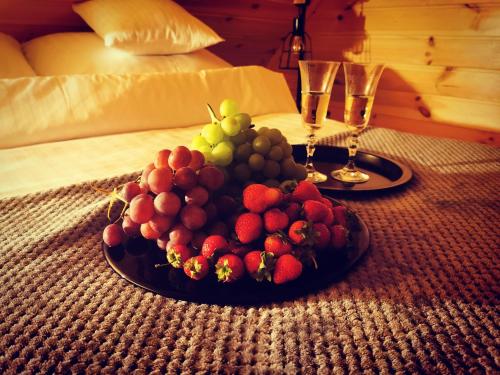 a plate of fruit on a table with two wine glasses at Domki przy plaży in Ryn