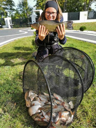 a woman sitting on the grass with a basket of lobsters at Domki przy plaży in Ryn