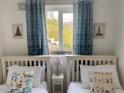 ein Schlafzimmer mit zwei Betten und einem Fenster mit blauen Vorhängen in der Unterkunft Bay View, Millendreth Looe Cornwall in Looe