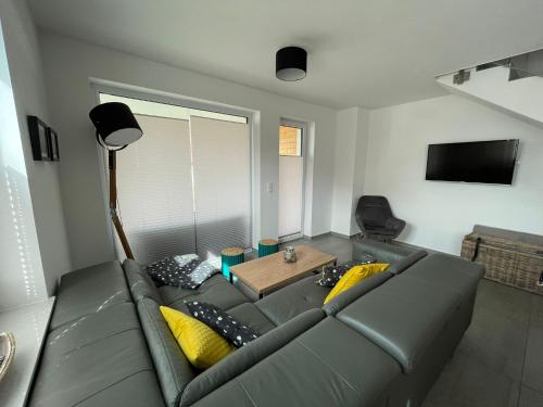 a living room with a gray couch with yellow pillows at Reusenhaus Nord in Breege