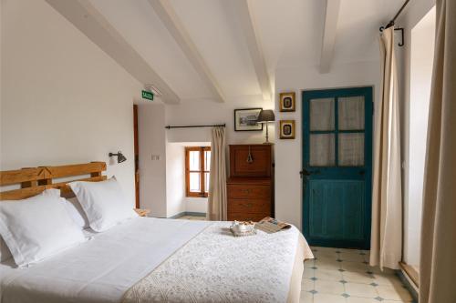 a bedroom with a white bed and a blue door at Cal Secretari Vell - Turismo de Interior in La Cabaneta