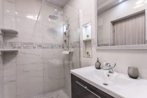 ein weißes Badezimmer mit Waschbecken und Dusche in der Unterkunft Royal Rose Gold Apartment in Vodice