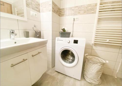 a white bathroom with a washing machine and a sink at Royal 27 apartman in Keszthely