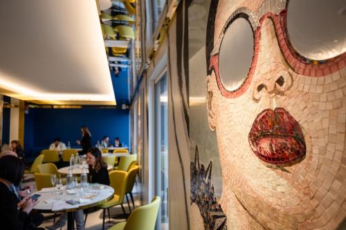 un mur en mosaïque dans un restaurant avec des personnes assises à table dans l'établissement Ghibli Hotel, à Civitanova Marche