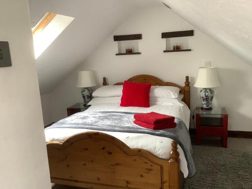 um quarto com uma cama de madeira e uma almofada vermelha em The Old Stables em Swansea