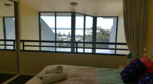 a bed with a doll laying on it in front of a window at Casablanca Penthouse Loft - Landmark 518 in Nelson Bay