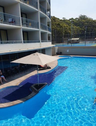a large swimming pool with an umbrella in a hotel at Casablanca Penthouse Loft - Landmark 518 in Nelson Bay