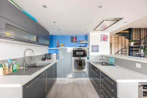 d'une cuisine avec des appareils électroménagers en acier inoxydable et des murs bleus. dans l'établissement Le Cockpit, à Courseulles-sur-Mer