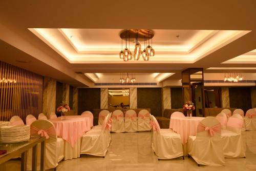 a banquet hall with white tables and chairs and a chandelier at HOTEL KLG ALTORIA in Chandīgarh