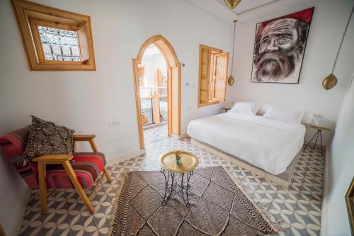 ein Schlafzimmer mit einem Bett, einem Tisch und einem Stuhl in der Unterkunft Riad Le Petit Joyau in Marrakesch