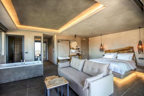 ein Schlafzimmer mit einem Bett, einem Sofa und einer Badewanne in der Unterkunft Meteora Heaven and Earth premium suites - Adults Friendly in Kalambaka