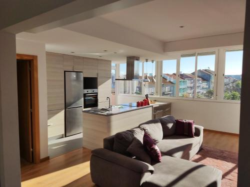 a living room with a couch and a kitchen at M&H Loft - Apartamento T2 em Setúbal in Setúbal
