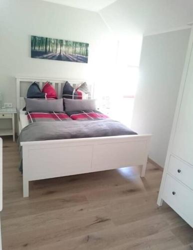 un letto bianco con cuscini rossi in una camera da letto di Ferienwohnung Inselblüte a Werder