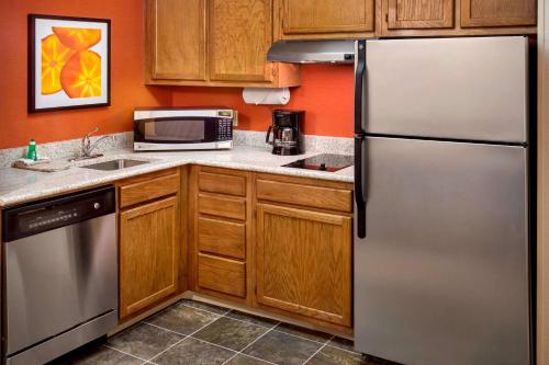 a kitchen with a stainless steel refrigerator and wooden cabinets at Sonesta ES Suites Allentown Bethlehem Airport in Bethlehem