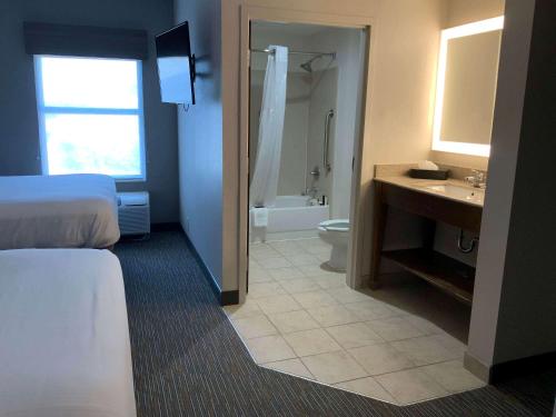 a hotel room with a bathroom with a bed and a sink at Wingate by Wyndham Jackson Ridgeland in Ridgeland