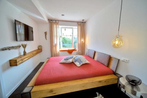 een slaapkamer met een rood bed en een raam bij FeWo Prora - Hiddensee 4.2 in Binz