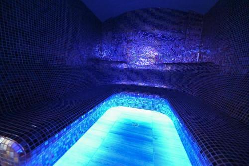 a swimming pool in a room with blue lights at Hotel Rudnik in Grudziądz