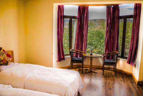 a bedroom with a bed and a table and windows at The Nature Residency - A Riverside Resort in Leh in Leh