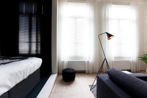 a bedroom with a bed and a lamp and a couch at Maison Nationale City Flats & Suites in Antwerp