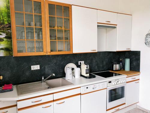 a kitchen with white cabinets and a sink at Schöne&zentrale Ferienwohnung in Schwelm in der Nähe von Wuppertal,Düsseldorf, Köln,Ruhrgebiet in Schwelm