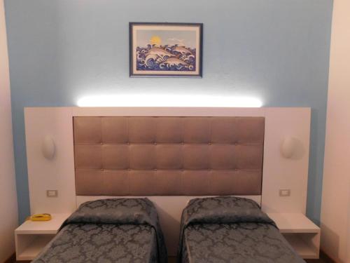 a bedroom with a large headboard and two beds at Hotel Oceano in Marina di Pietrasanta