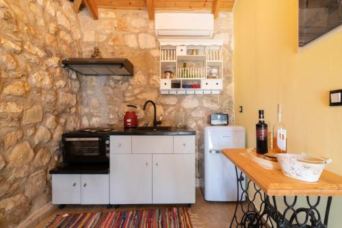 a kitchen with white cabinets and a stone wall at Dorothea Villa in Zakynthos Town
