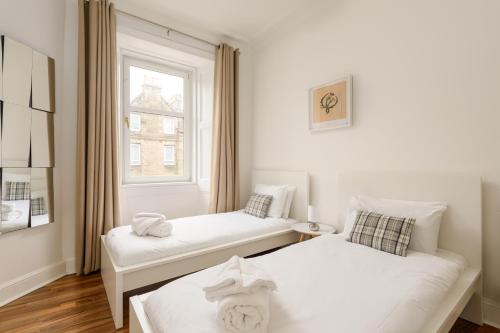 2 camas en una habitación pequeña con ventana en The London Road Apartment - 2BR/1BA en Edimburgo