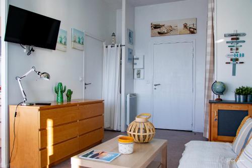 a living room with a couch and a dresser and a tv at Le COURLIS vue panoramique sur la mer, balcons in Ault