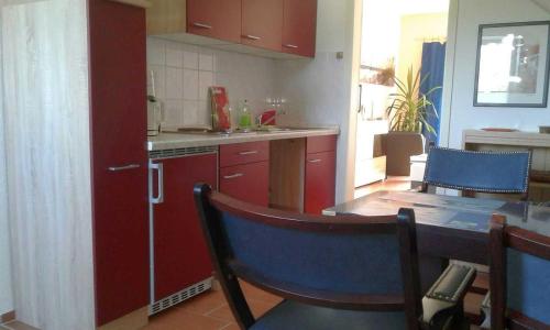 a kitchen with red cabinets and a table and chairs at Rügen Fewo 284 in Neu Mukran