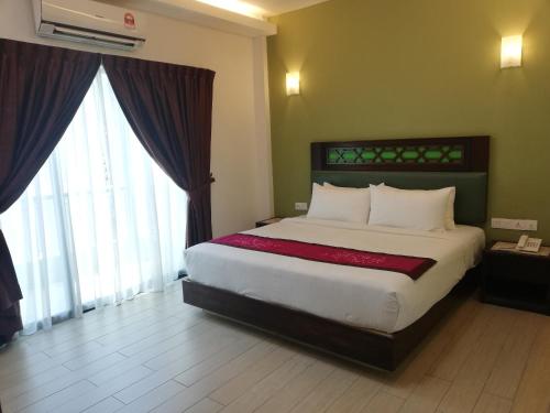 
a hotel room with a large bed and a large window at Swiss Hotel Heritage Boutique Melaka in Malacca
